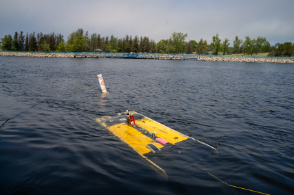 Autonomous underwater vehicle is mostly submerged near the surface of the water.